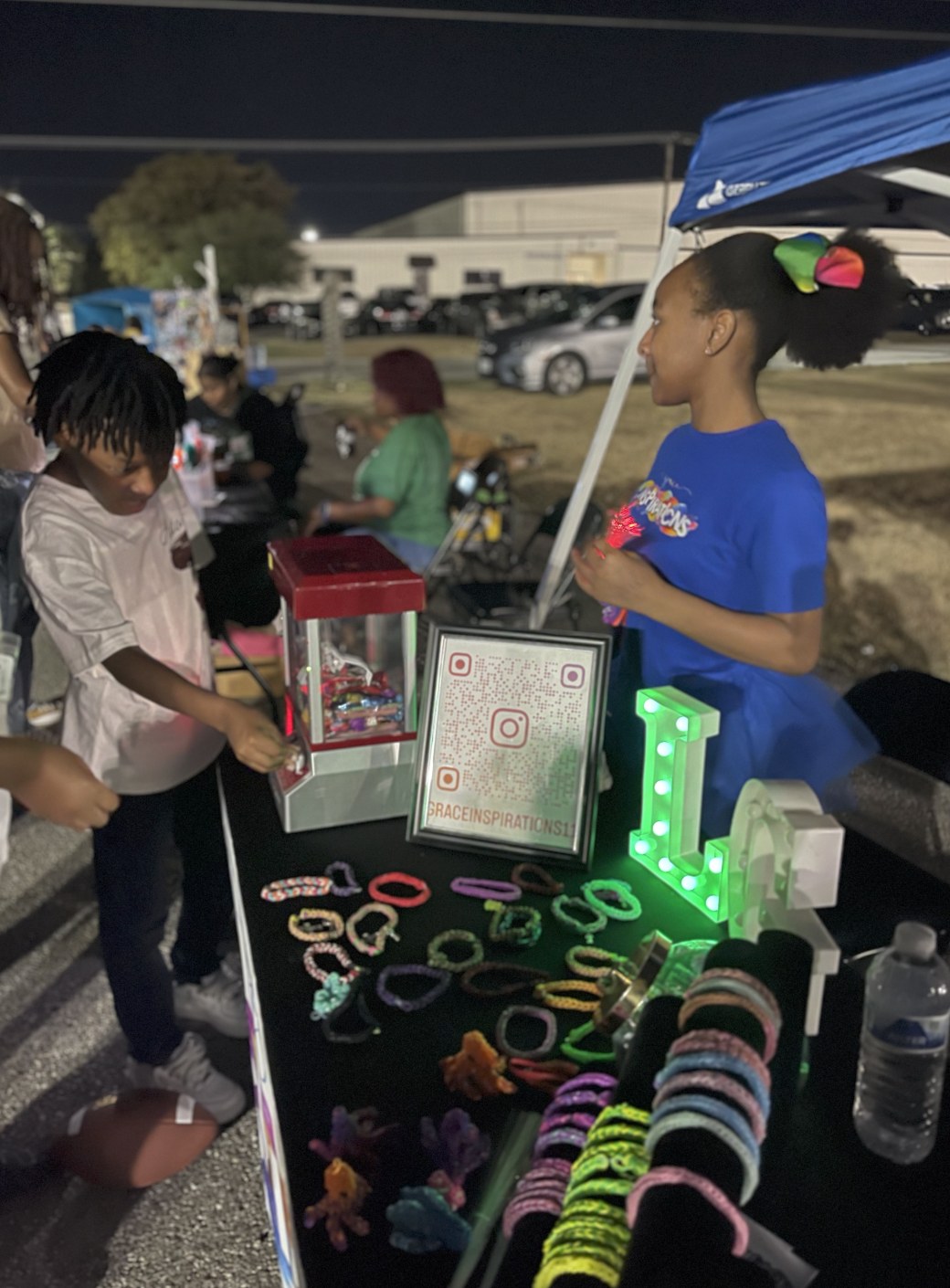 Grace helping customers at her bracelet booth during an evening market