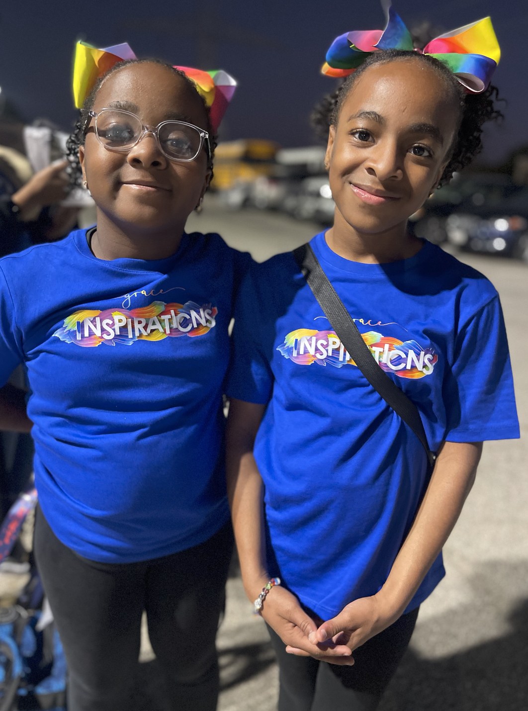Grace and a teammate wearing matching Grace's Inspirations shirts and rainbow bows